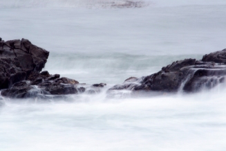 ocean rocks waves form waterfalls, white mist